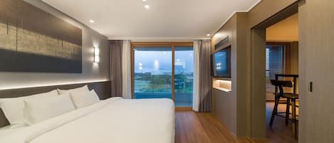 Quarto de hotel moderno com uma cama grande, televisão e varanda com vista para a cidade.