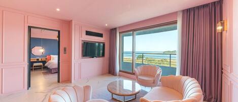 A pink-themed room with a balcony, a round table, and two armchairs.