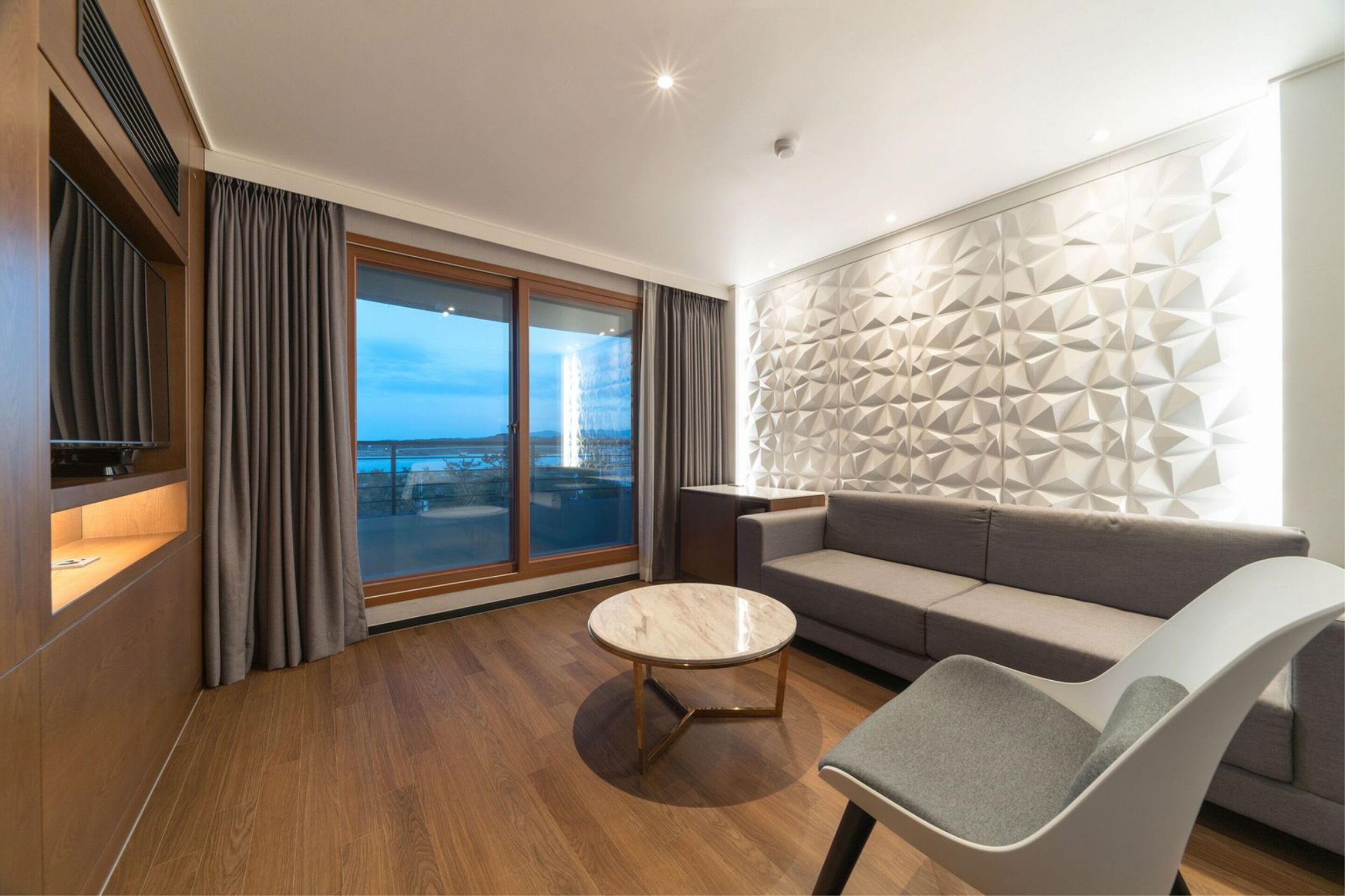 A modern living room with a sofa, a round coffee table, and a TV on a wooden cabinet.