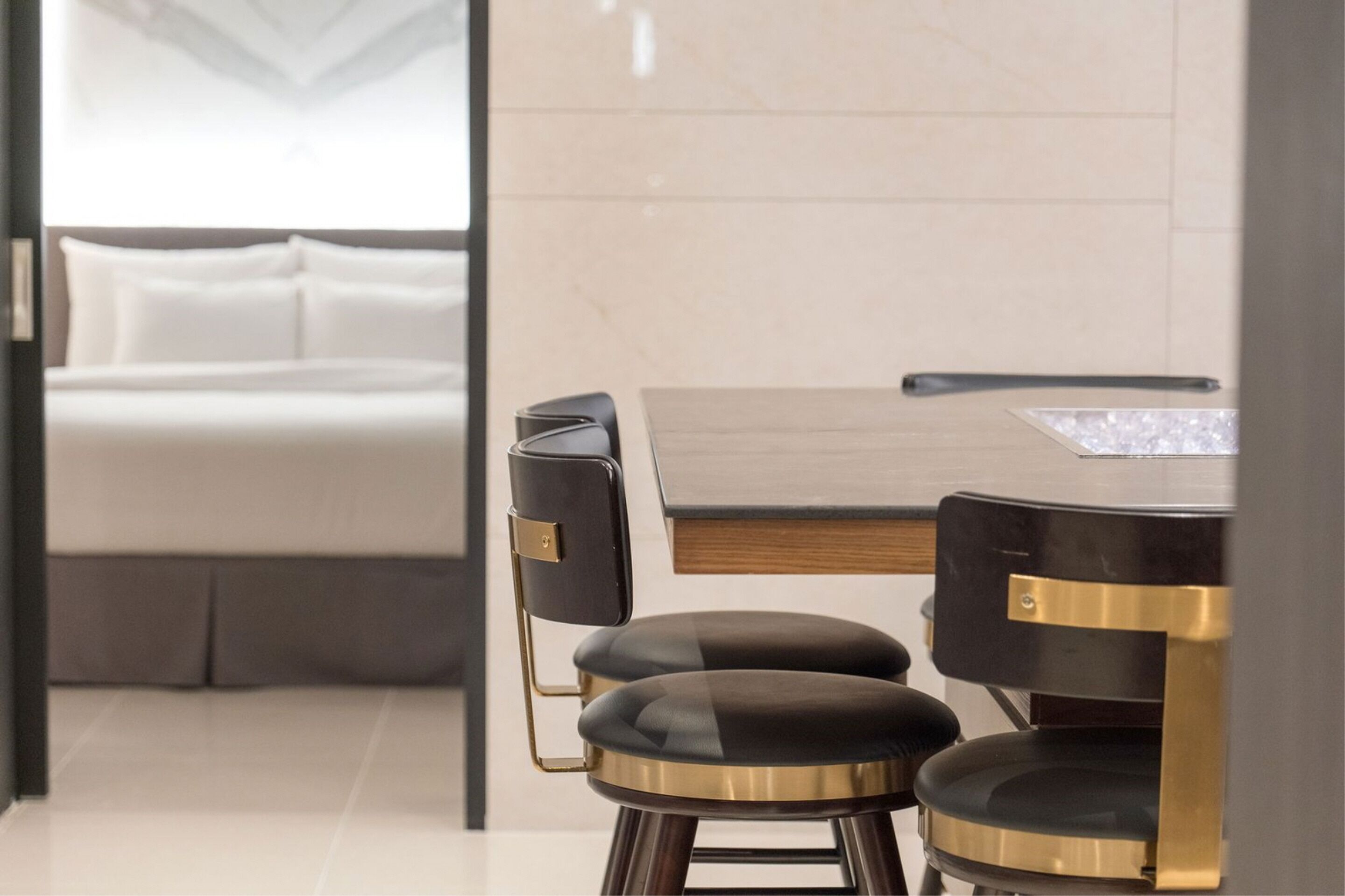 Una habitación de hotel moderna con una cama, una mesa de comedor con dos sillas y vista al interior de la habitación.