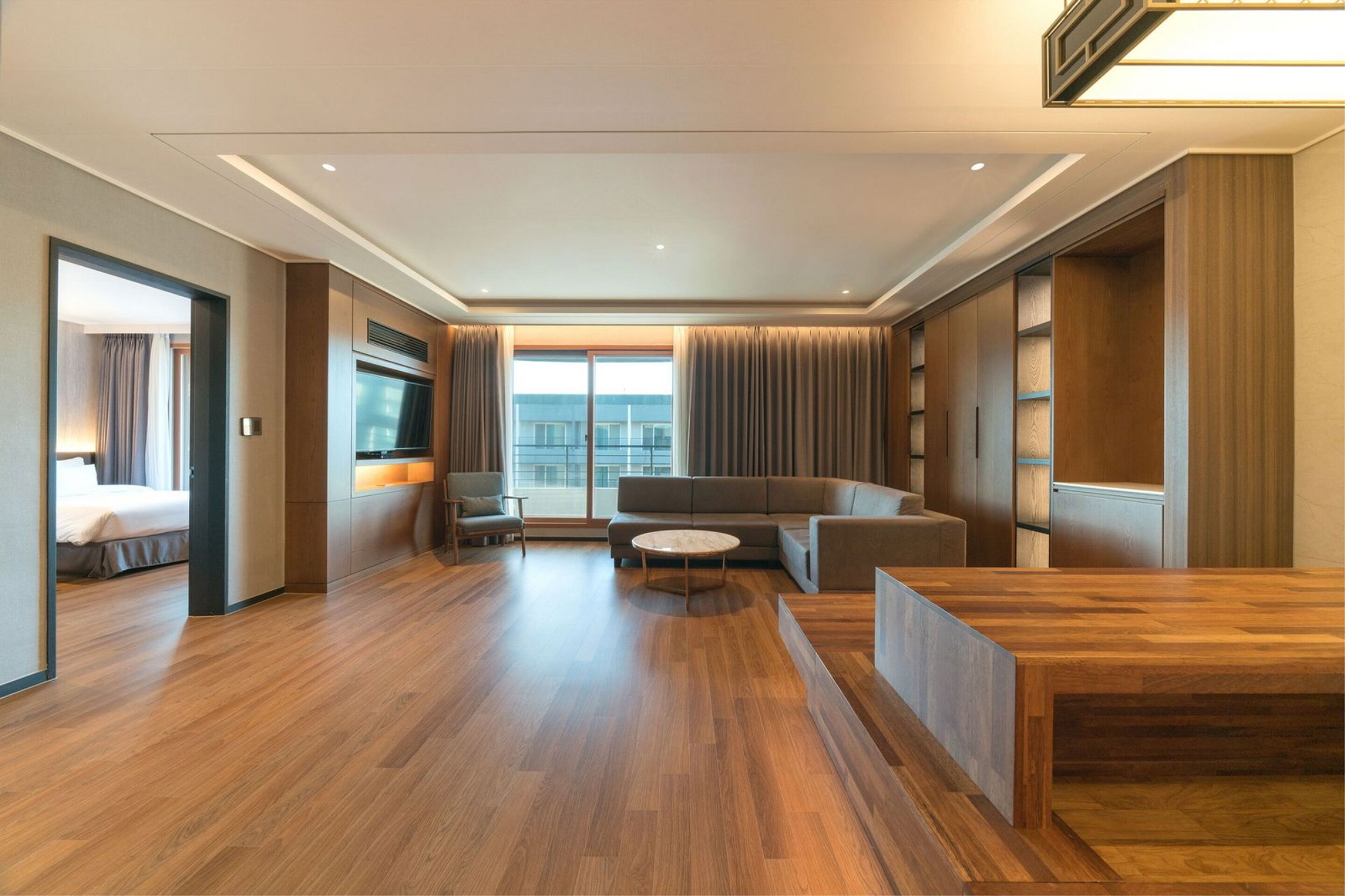 Una habitación de hotel moderna con piso de madera, un sofá, una mesa de centro y un televisor.