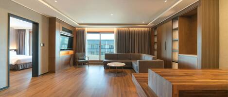 Una habitación de hotel moderna con piso de madera, un sofá, una mesa de centro y un televisor.