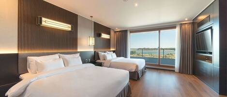 A hotel room with two beds, a large window with a view, and a flat-screen TV.