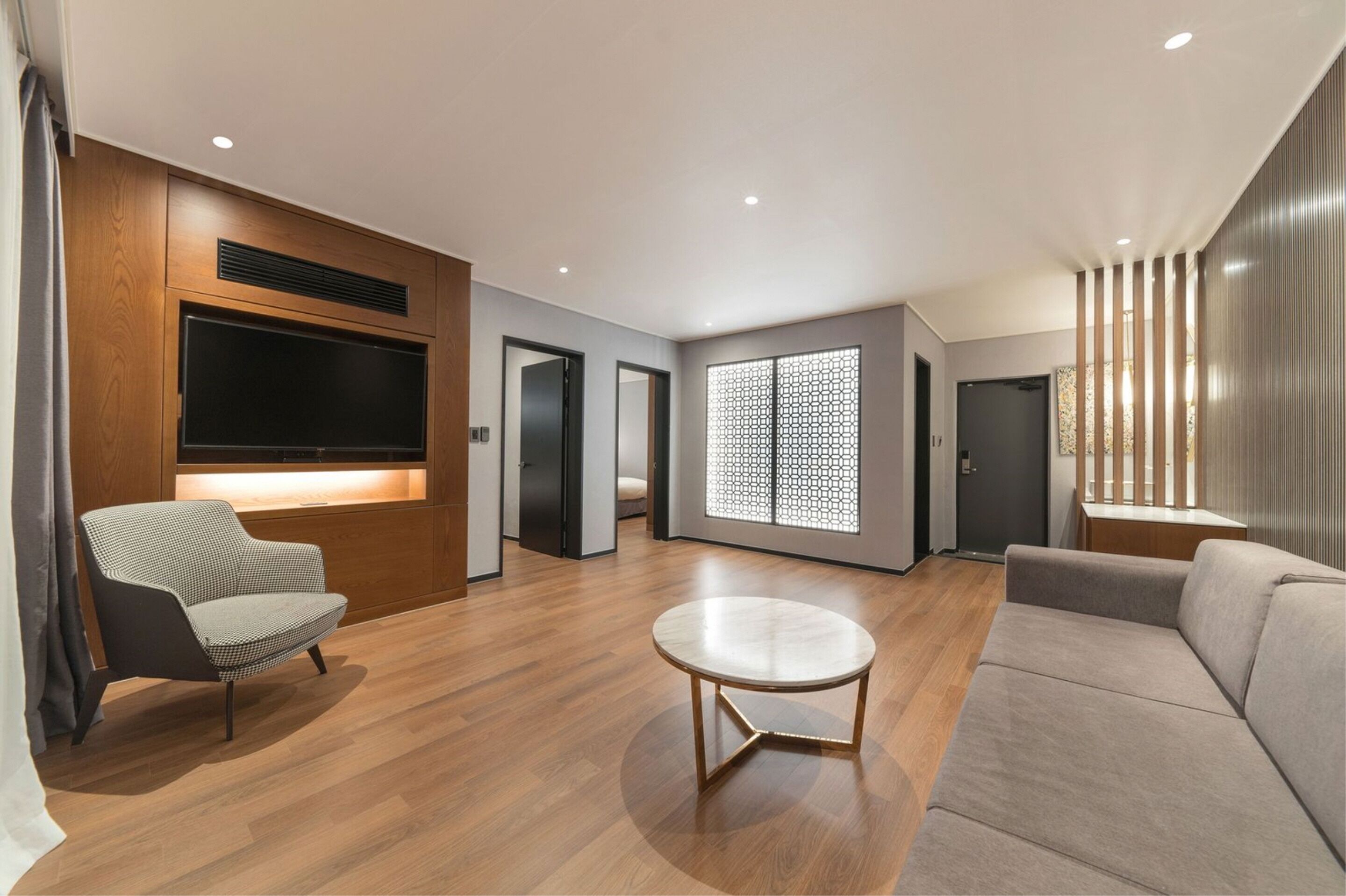 A modern living room with a flat-screen TV, a round coffee table, and a sofa.