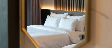 A neatly made bed with white linens in a hotel room.