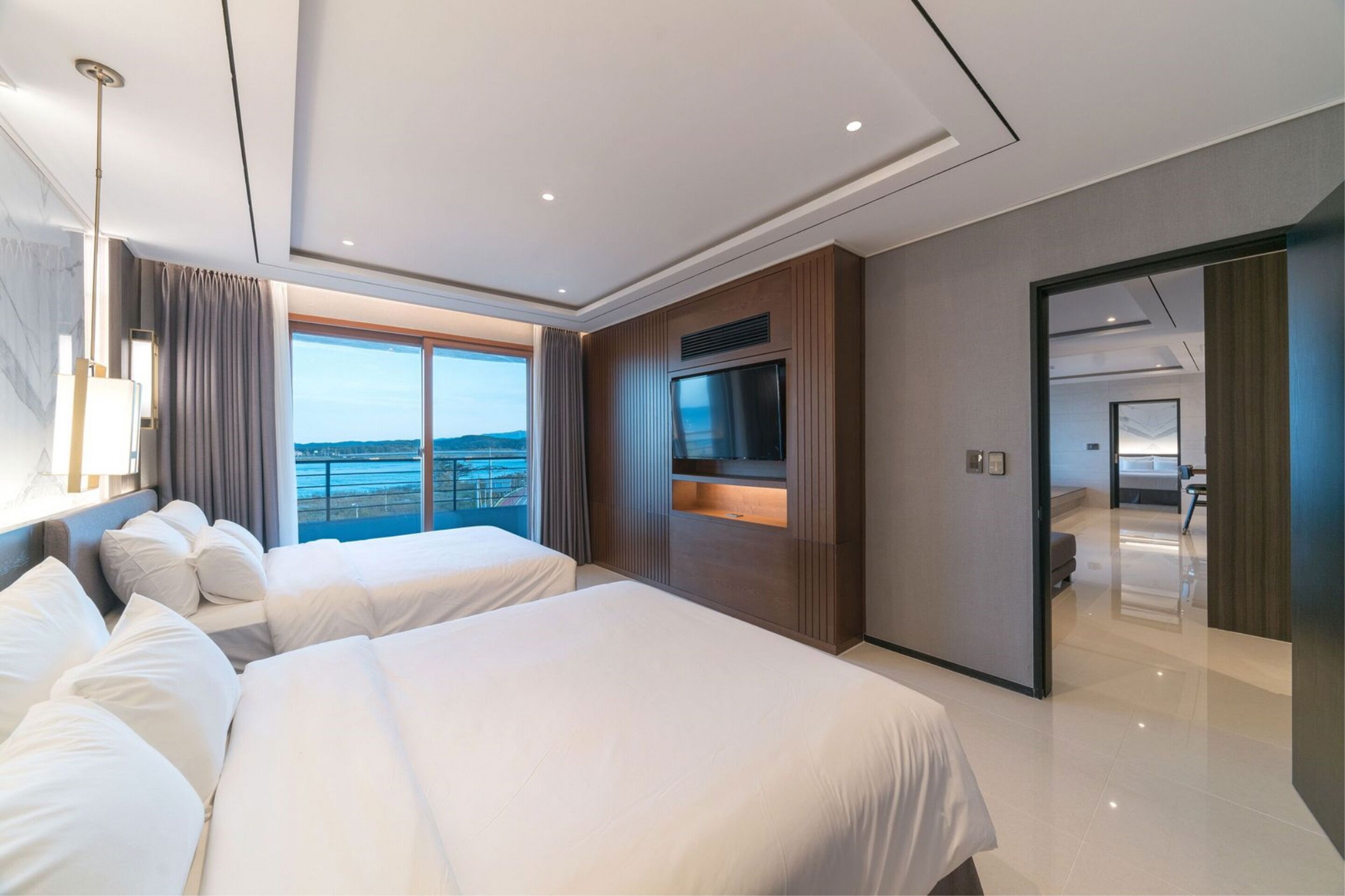 Una camera d'albergo moderna con due letti grandi, una televisione e vista sul mare.