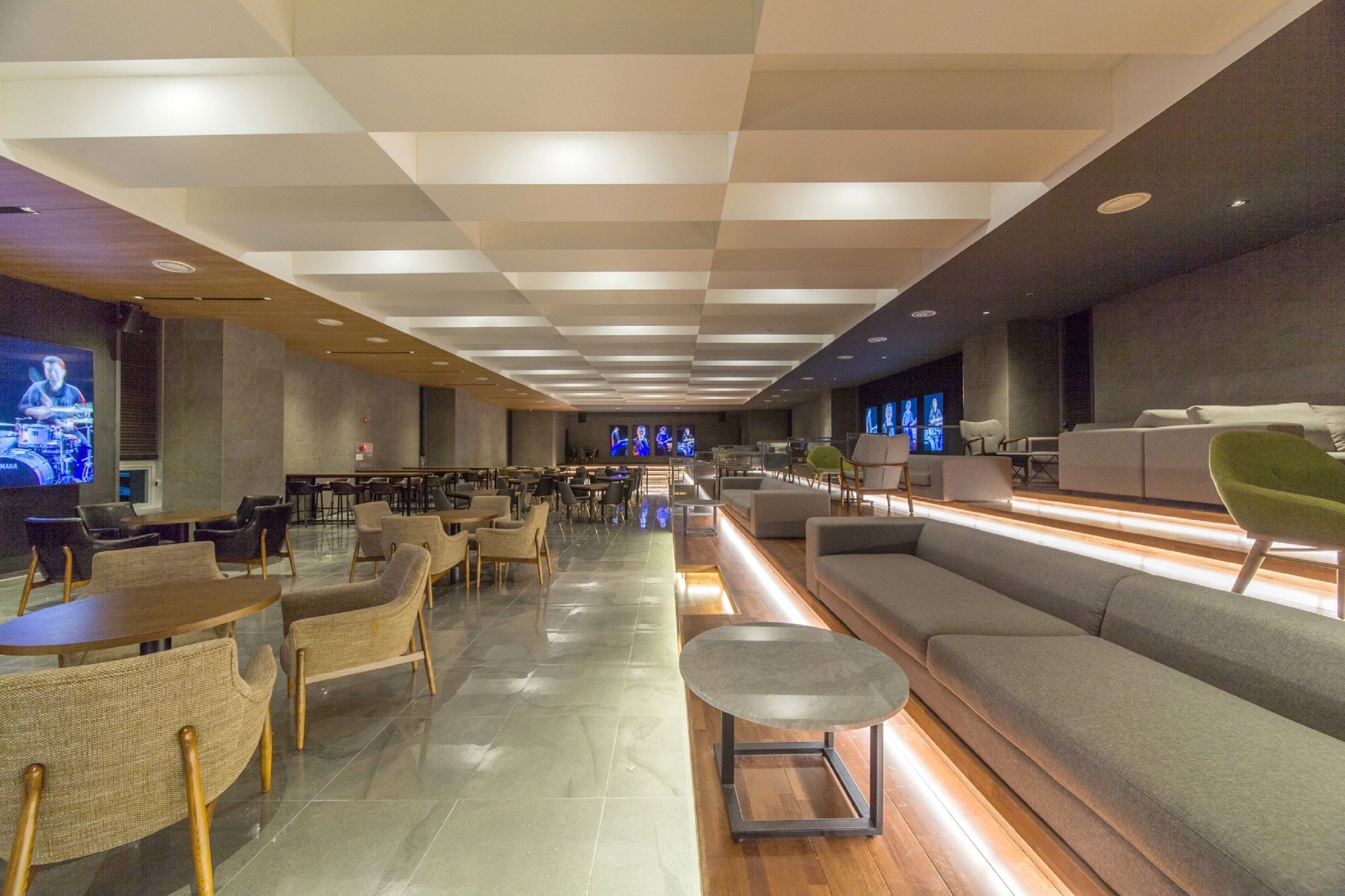 A modern lounge area with seating arrangements, a long counter, and a stage in the background.