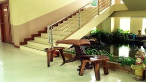 A staircase with a metal railing, a small indoor pond with plants, and wooden furniture. - Amarin Grand Rayong (Rayong)