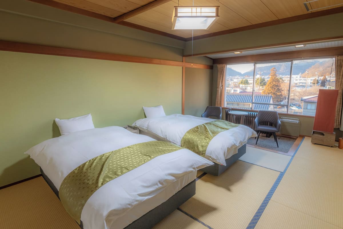 Ett hotellrum med två sängar, ett skrivbord och utsikt över stadsbilden.