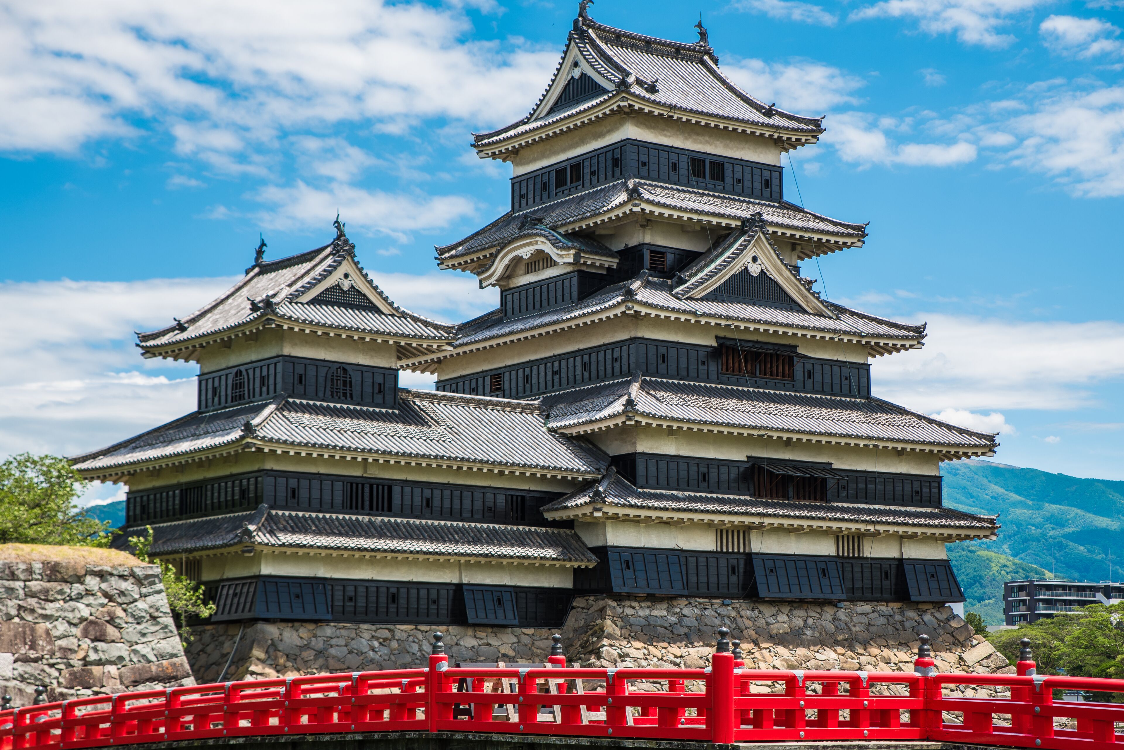 A traditional Japanese castle with multiple tiers and a red bridge in front.
