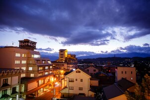 Un paisaje urbano al anochecer con edificios iluminados y un cielo nublado.
