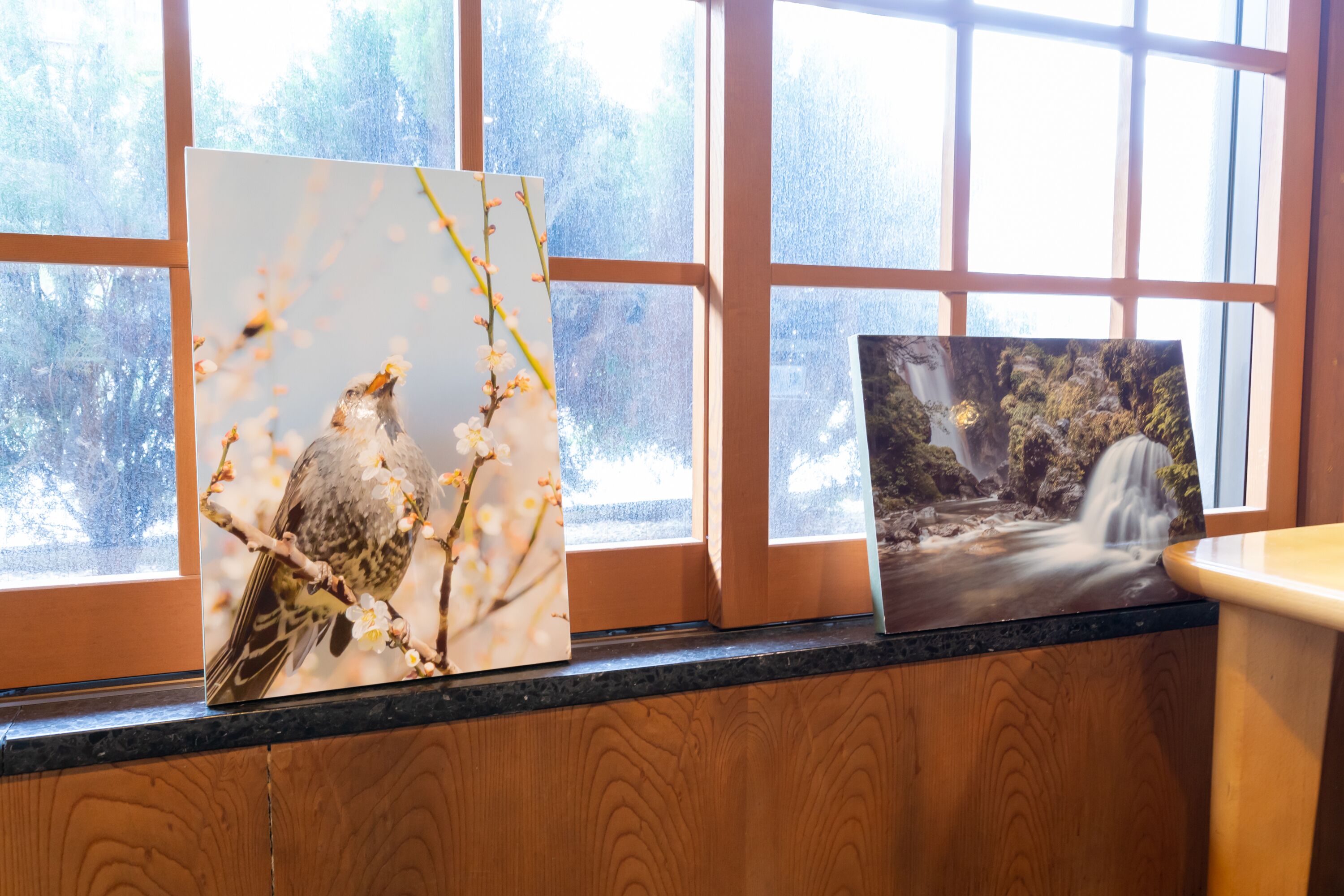 Two framed artworks on a window ledge.