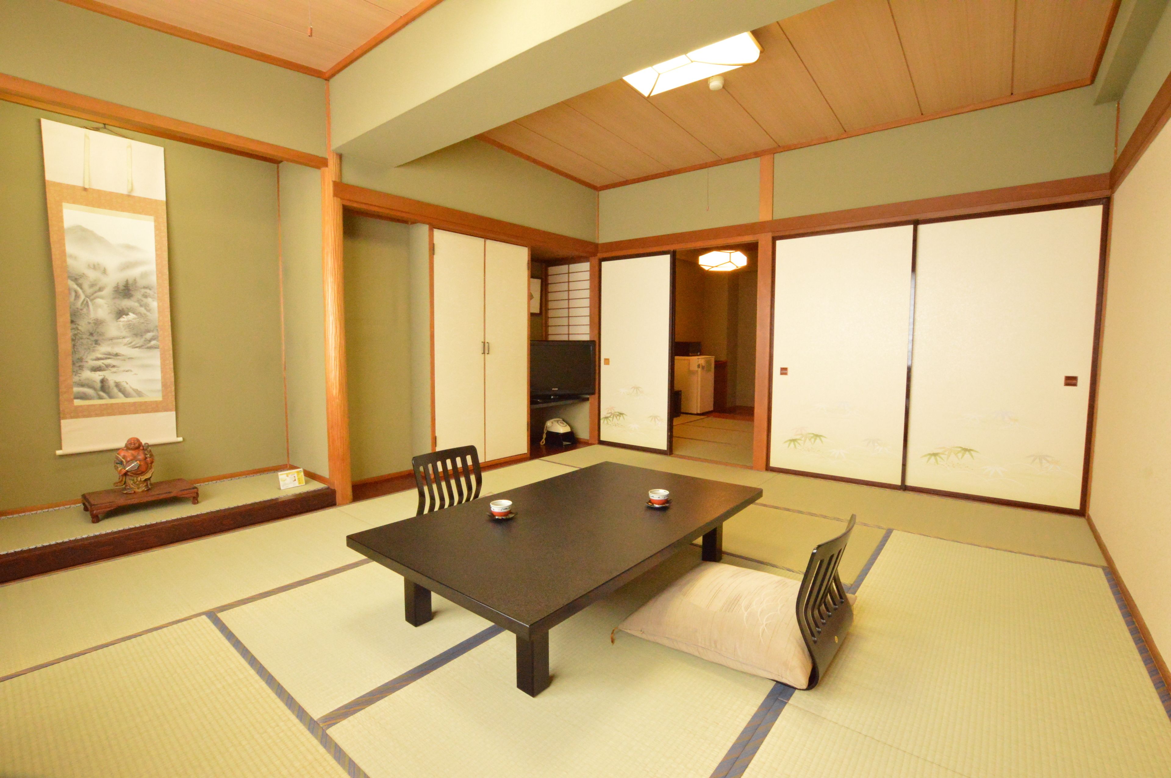 A traditional Japanese tatami room with a low table, tatami mats, sliding doors, and a shoji screen.