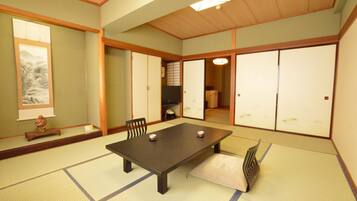 A traditional Japanese tatami room with a low table, tatami mats, sliding doors, and a shoji screen.