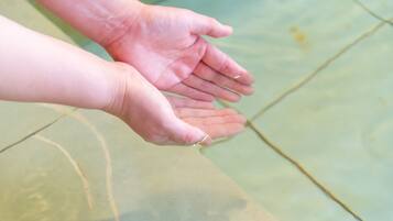 A close-up of hands reaching towards each other over a tiled floor.