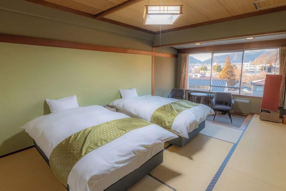 Ett hotellrum med två sängar, ett skrivbord och utsikt över bergen.