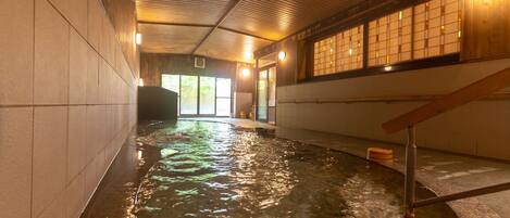 A spa area with a hot spring, wooden walls, and a tiled floor.