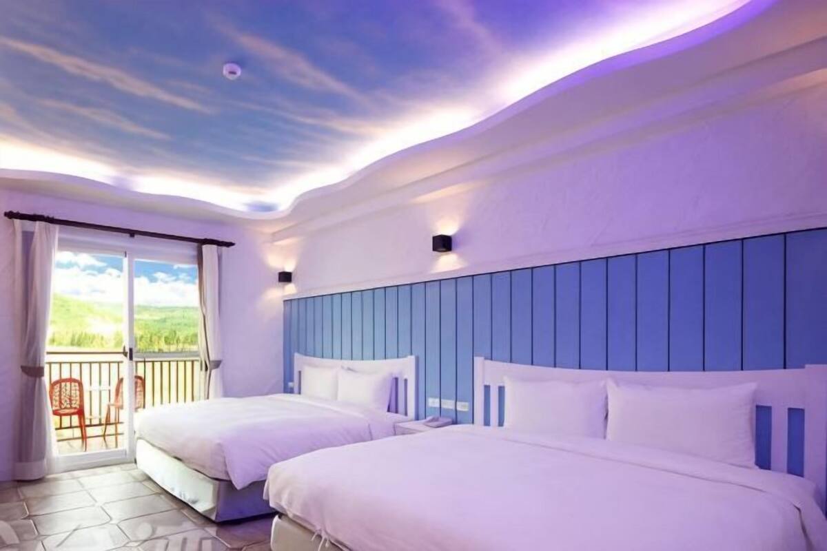 Habitación de hotel con dos camas, un balcón y vistas, además de un diseño de techo moderno.