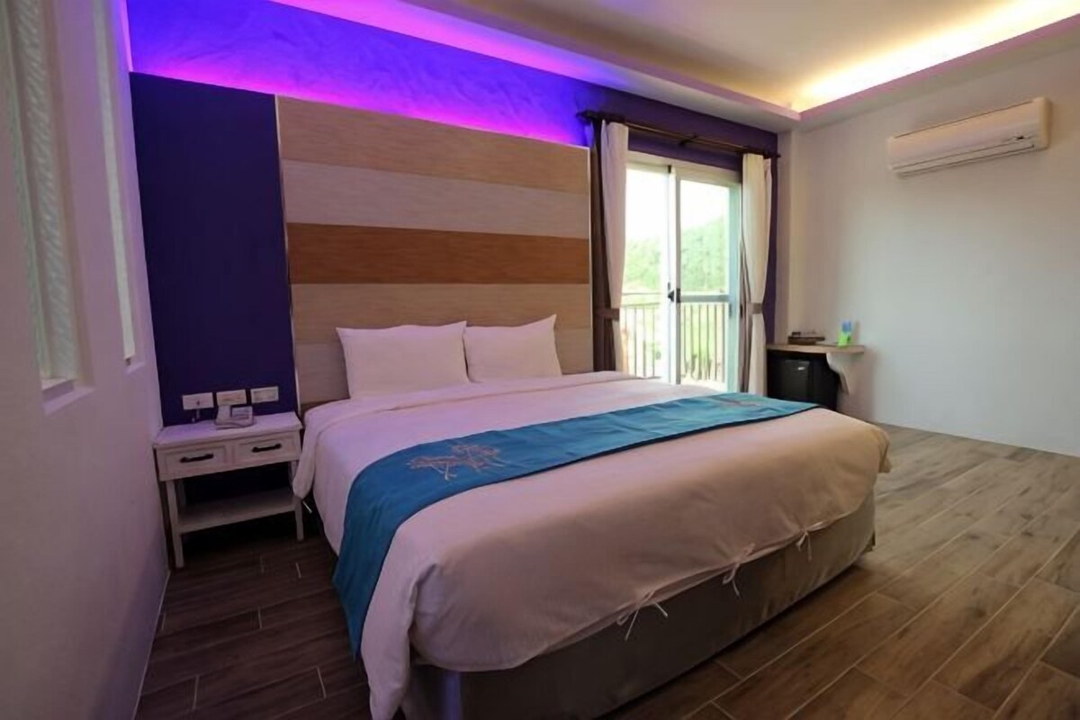 Een slaapkamer met een bed, nachtkastje en een raam met gordijnen.