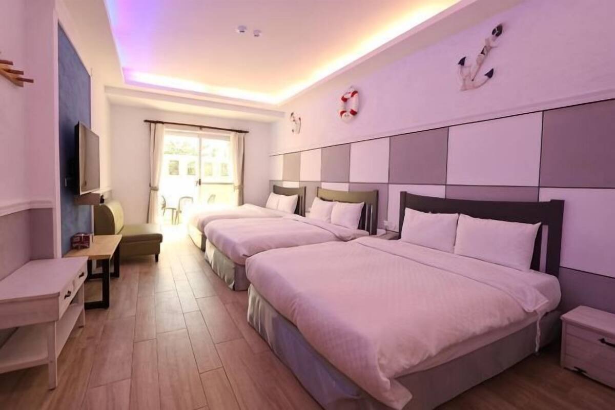 Habitación de hotel con dos camas, un escritorio, una silla y un televisor.