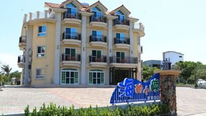 A multi-story hotel with balconies, a tiled entrance area, and a signboard. - Island On The Sea (Hengchun)