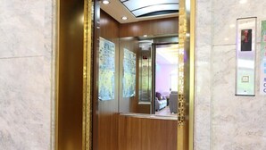 An elevator interior with wooden paneling, a marble floor, and a digital display showing the floor level. - Island On The Sea (Hengchun)