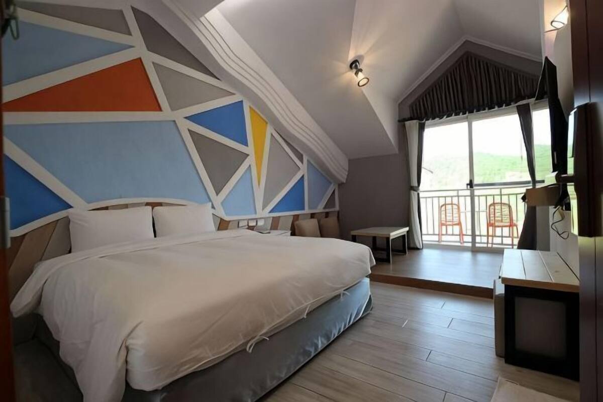 Un dormitorio con cama, escritorio, silla y balcón con vistas.