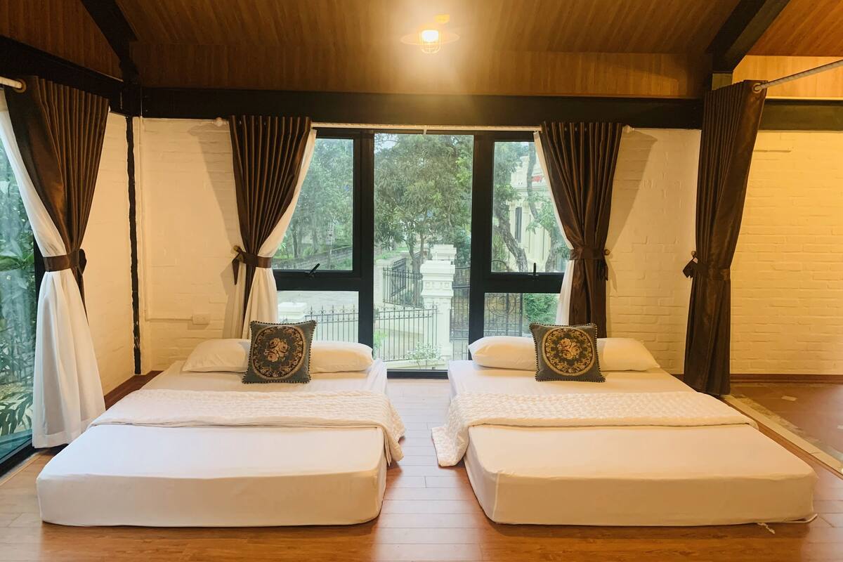 Una habitación con dos camas, ventanas amplias y vistas al exterior.