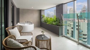 Un balcón con mobiliario de mimbre, una bañera blanca y vista a la ciudad.
