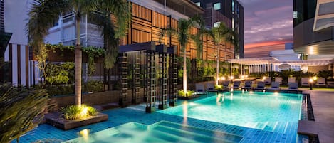 Una piscina al aire libre, sombrillas, sillones reclinables de piscina