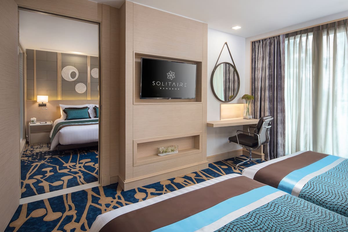 A hotel room with a bed, a desk, a TV, and a mirror.