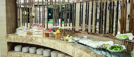 Una barra de buffet con diferentes alimentos y platos sobre una encimera de mármol.