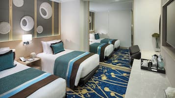 A hotel room with two beds, a desk, a mirror, and a decorative wall.