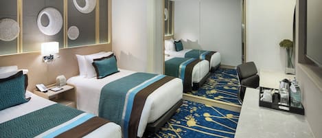 A hotel room with two beds, a desk, a mirror, and a decorative wall.