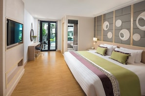 Ein modernes Hotelzimmer mit einem großen Bett, einem Schreibtisch, einem Fernseher und Blick ins Freie.