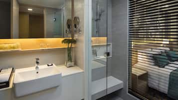 A modern bathroom with a large mirror, a white sink, and a glass-enclosed shower area.