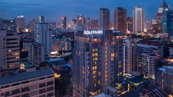 A cityscape with a prominent building labeled "SOLITAIRE" featuring a modern architectural design with multiple floors and illuminated windows.