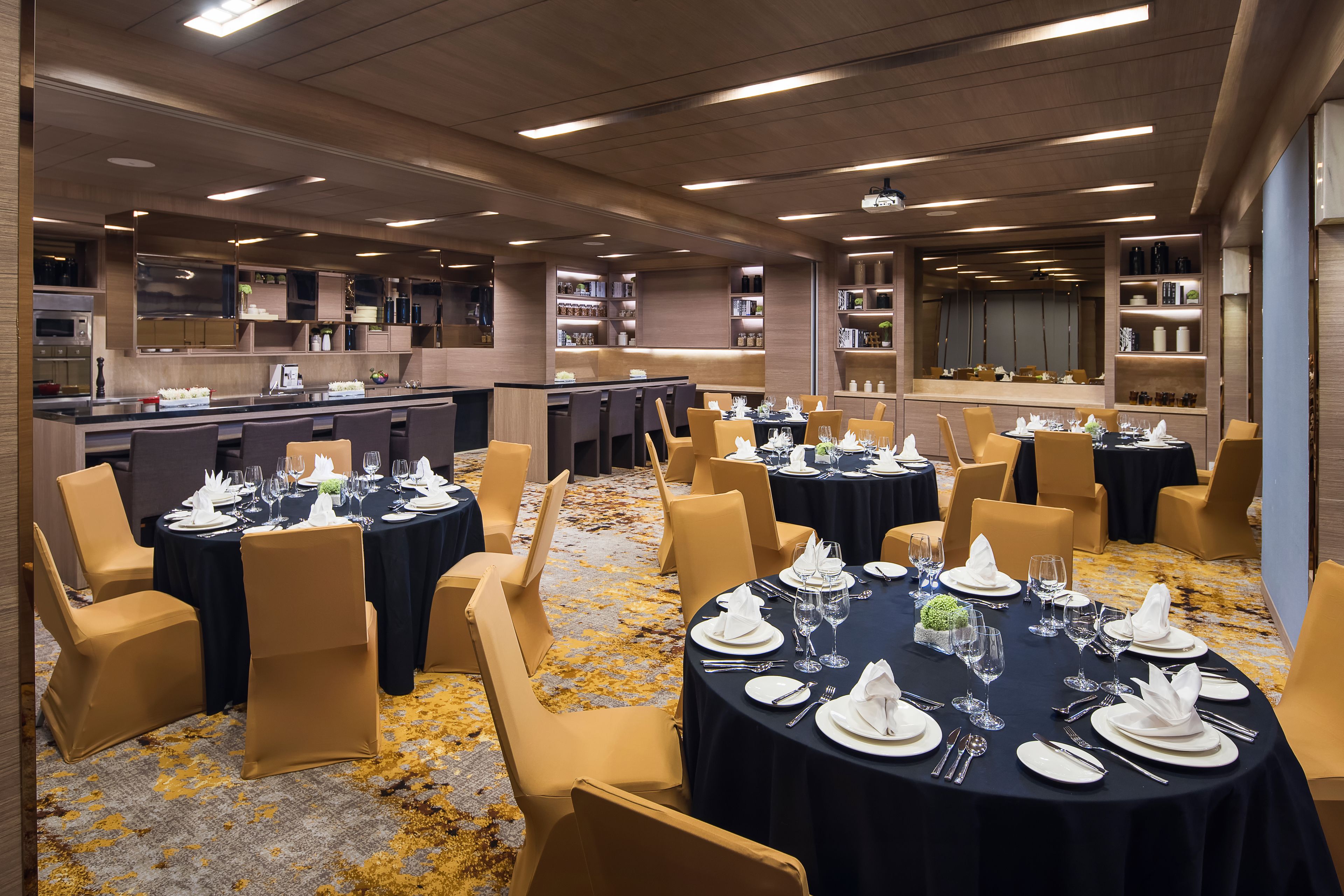 A hotel dining area with round tables set for a meal, equipped with chairs, and surrounded by shelves with books and decorative items.