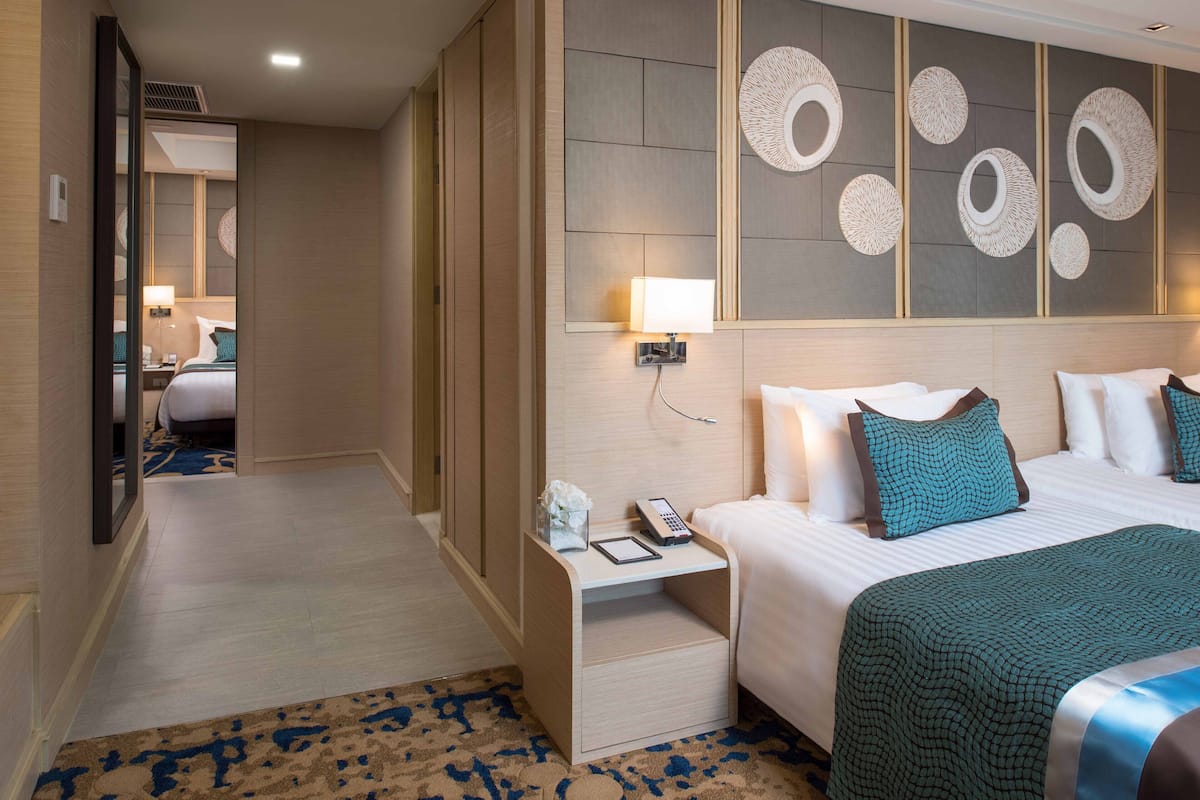 A hotel room with a bed, bedside table, lamp, and a wall with circular designs.