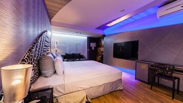 A modern hotel room with a large bed, a desk, and a flat-screen TV.