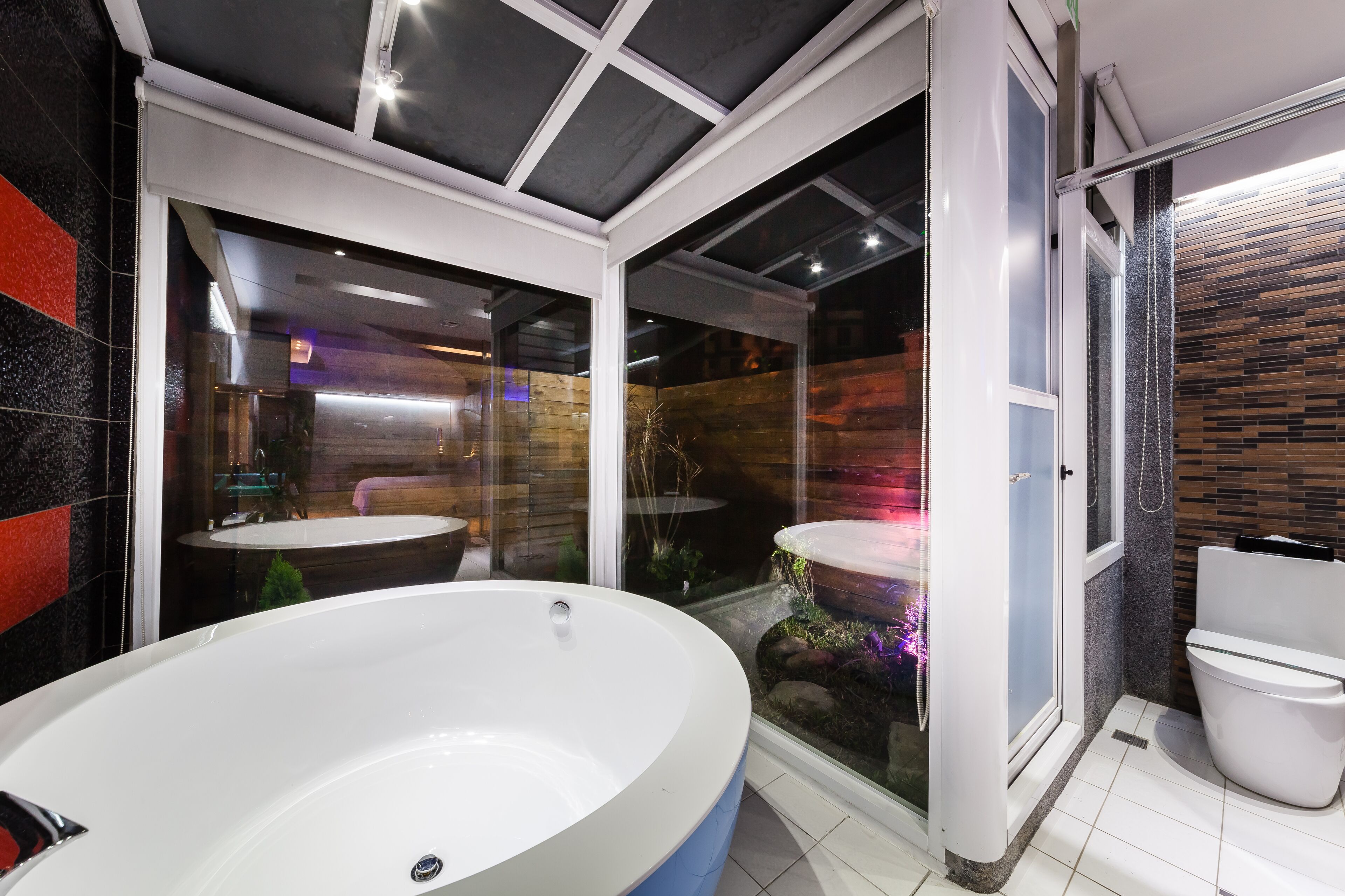 A modern bathroom with a large freestanding bathtub, a glass-enclosed shower area, and a white toilet.