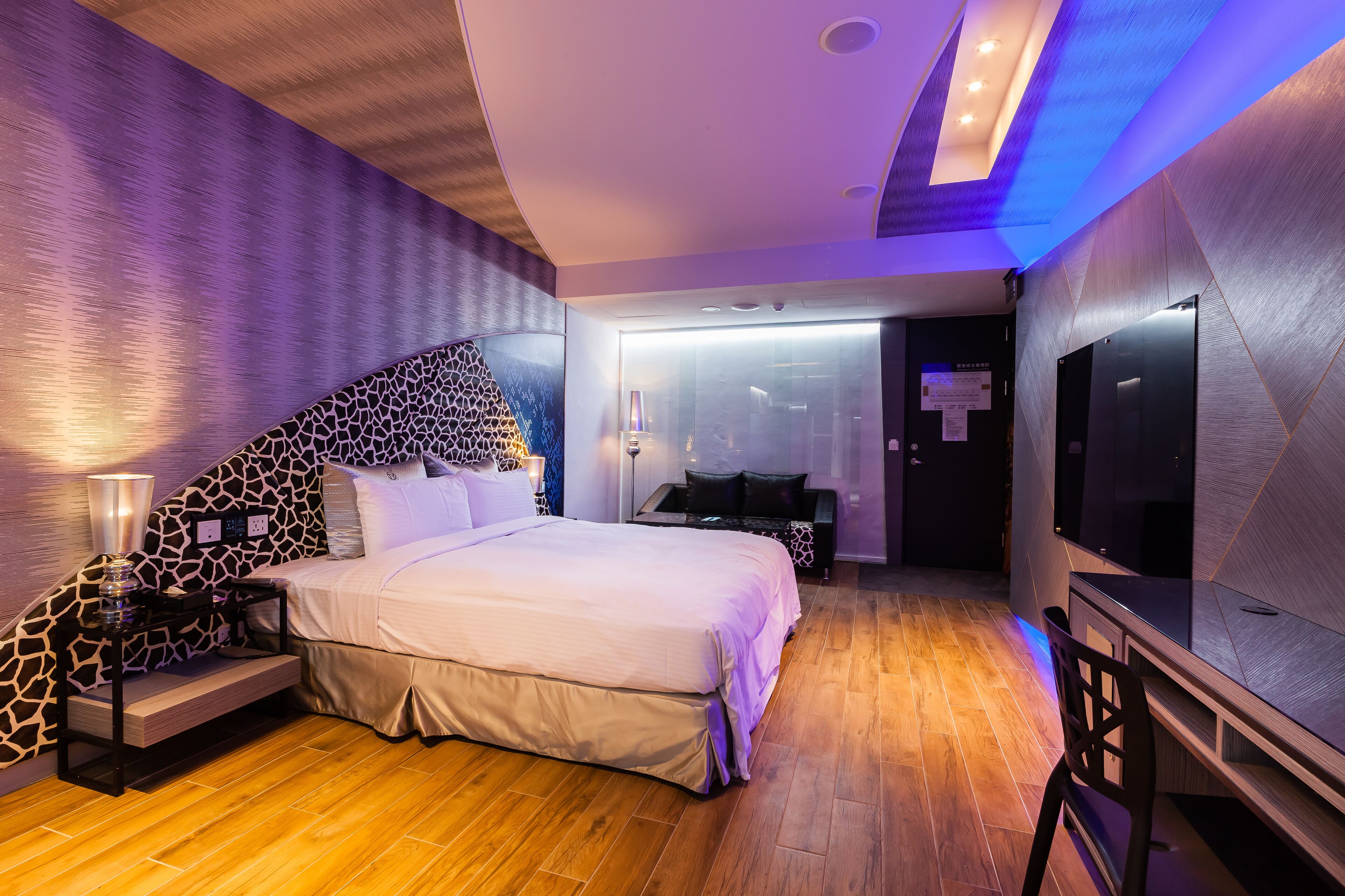A modern bedroom with a large bed, a TV, and a desk.
