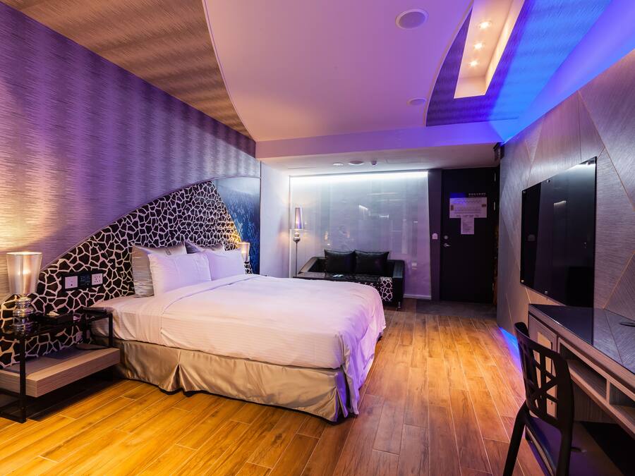 A modern bedroom with a large bed, a TV, and a desk.