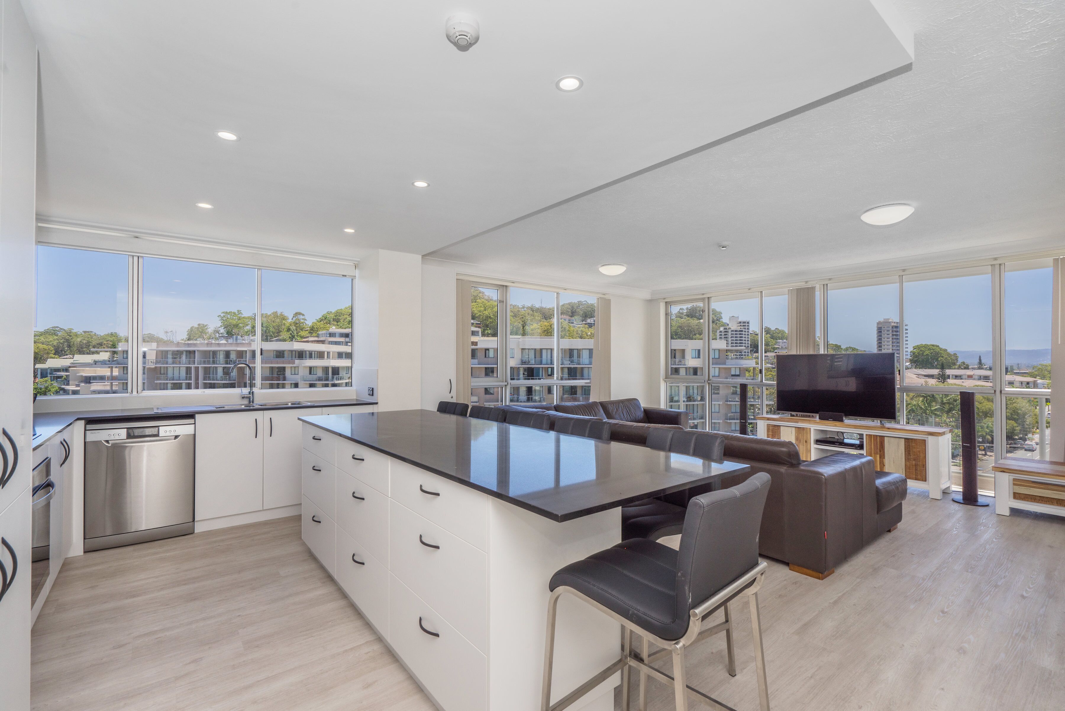 Cocina moderna con una isla grande, electrodomésticos integrados y un comedor con televisor y asientos.