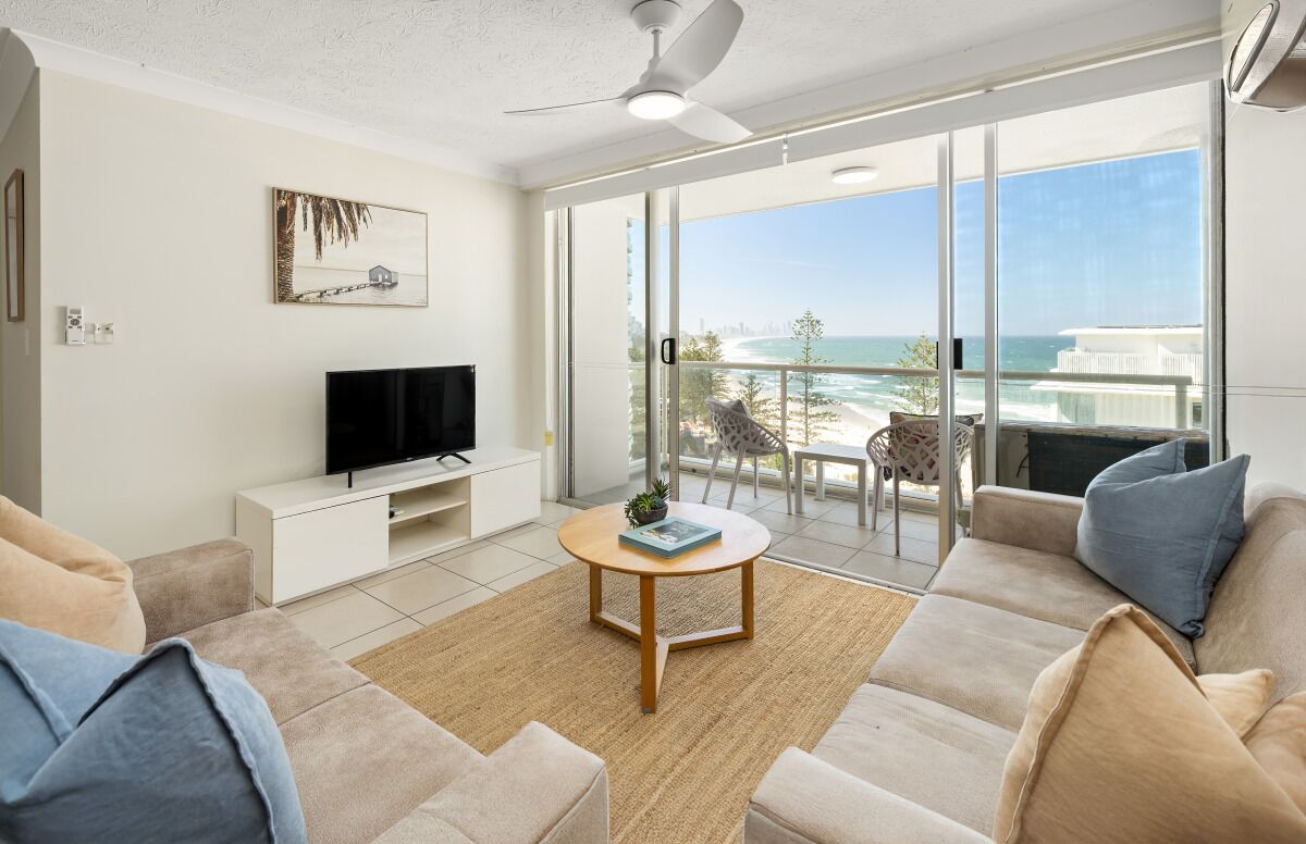 A modern living room with a flat-screen TV, a round coffee table, and a sofa.