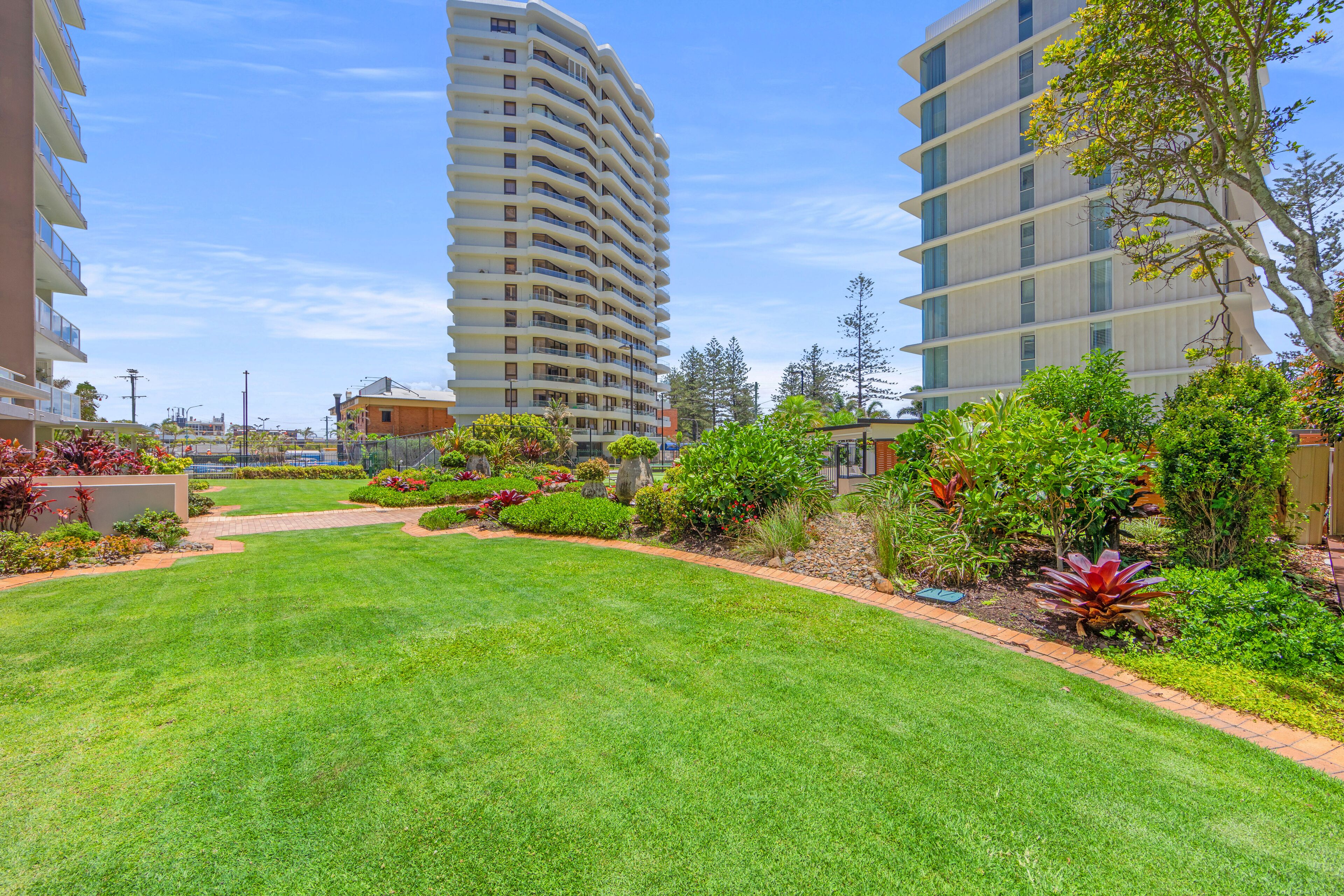 A well-maintained lawn with a pathway leading to a building with a curved facade.