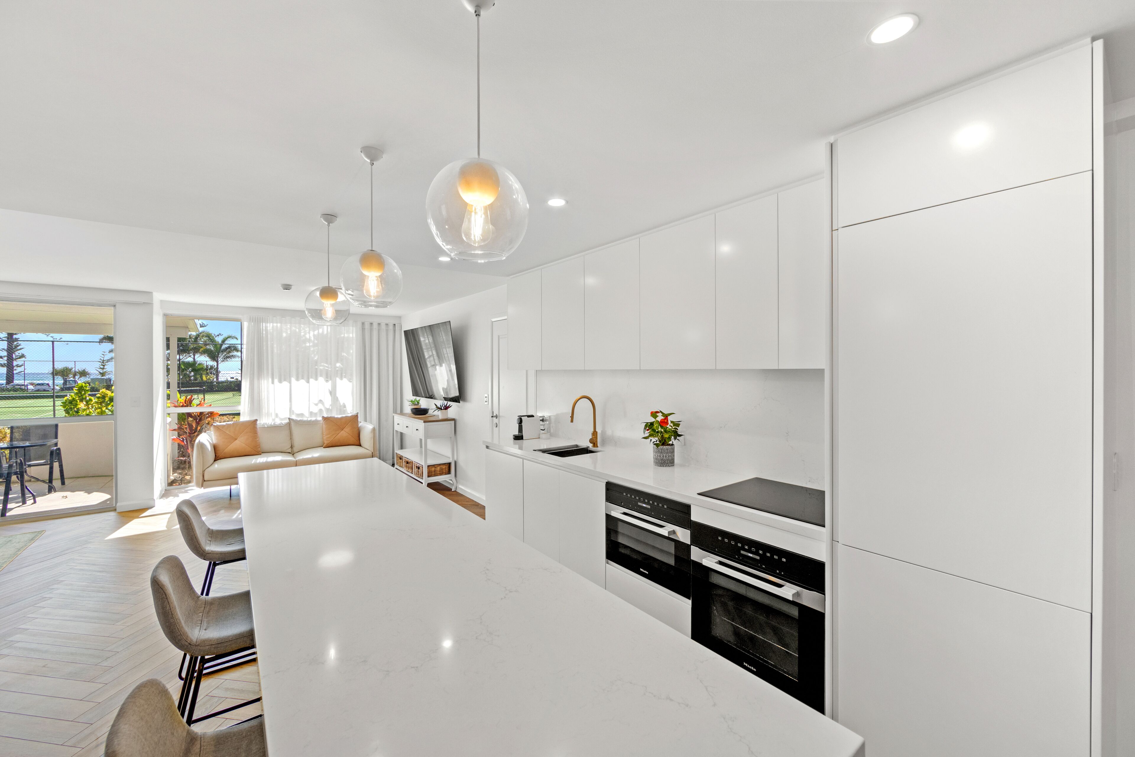 Una cocina moderna con armarios blancos, una isla grande e iluminación colgante.