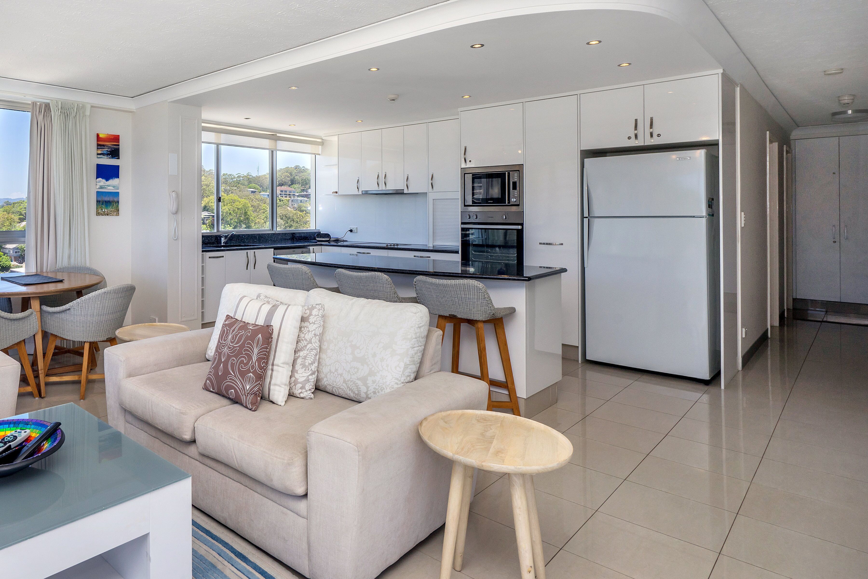 A modern kitchen with white cabinets, a large refrigerator, and a microwave.