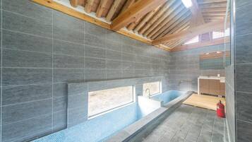 Relax in a spacious bathtub with an unobstructed view, surrounded by large tiles and natural light.