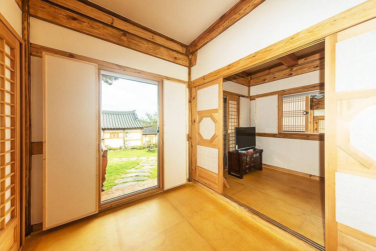 Una habitación tradicional japonesa con puertas correderas, un televisor y vistas a un jardín.